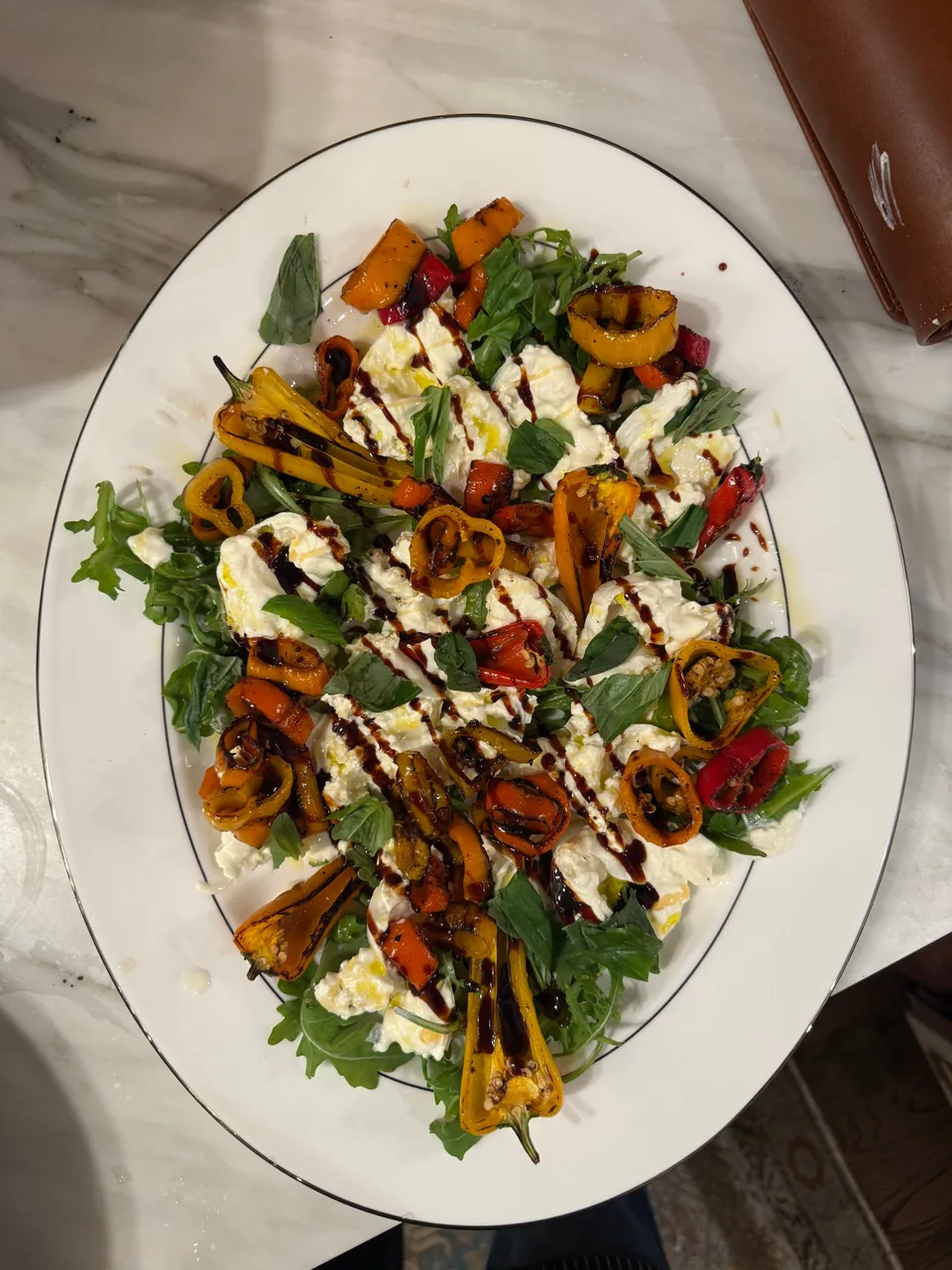 Platter of burrata with blistered sweet peppers, arugula, basil and balsamic