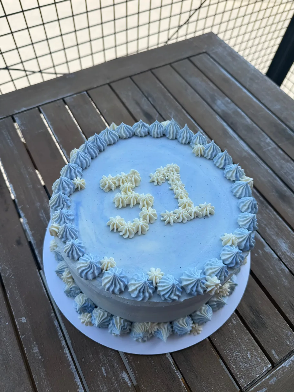 Pale blue buttercream birthday cake piped with the number 31 and a border of blue and cream rosettes