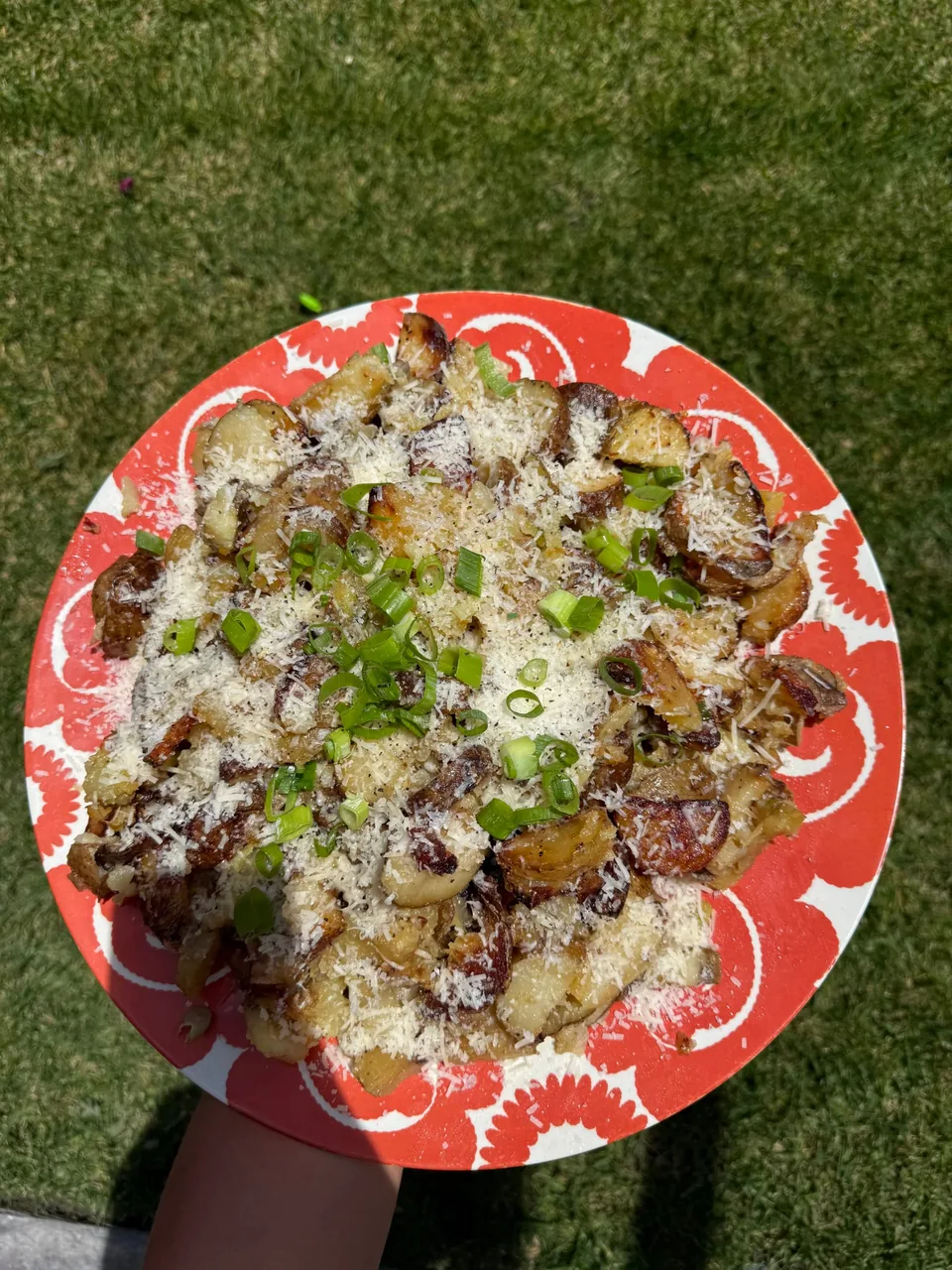 Plate of crispy smashed potatoes topped with grated parmesan and scallions