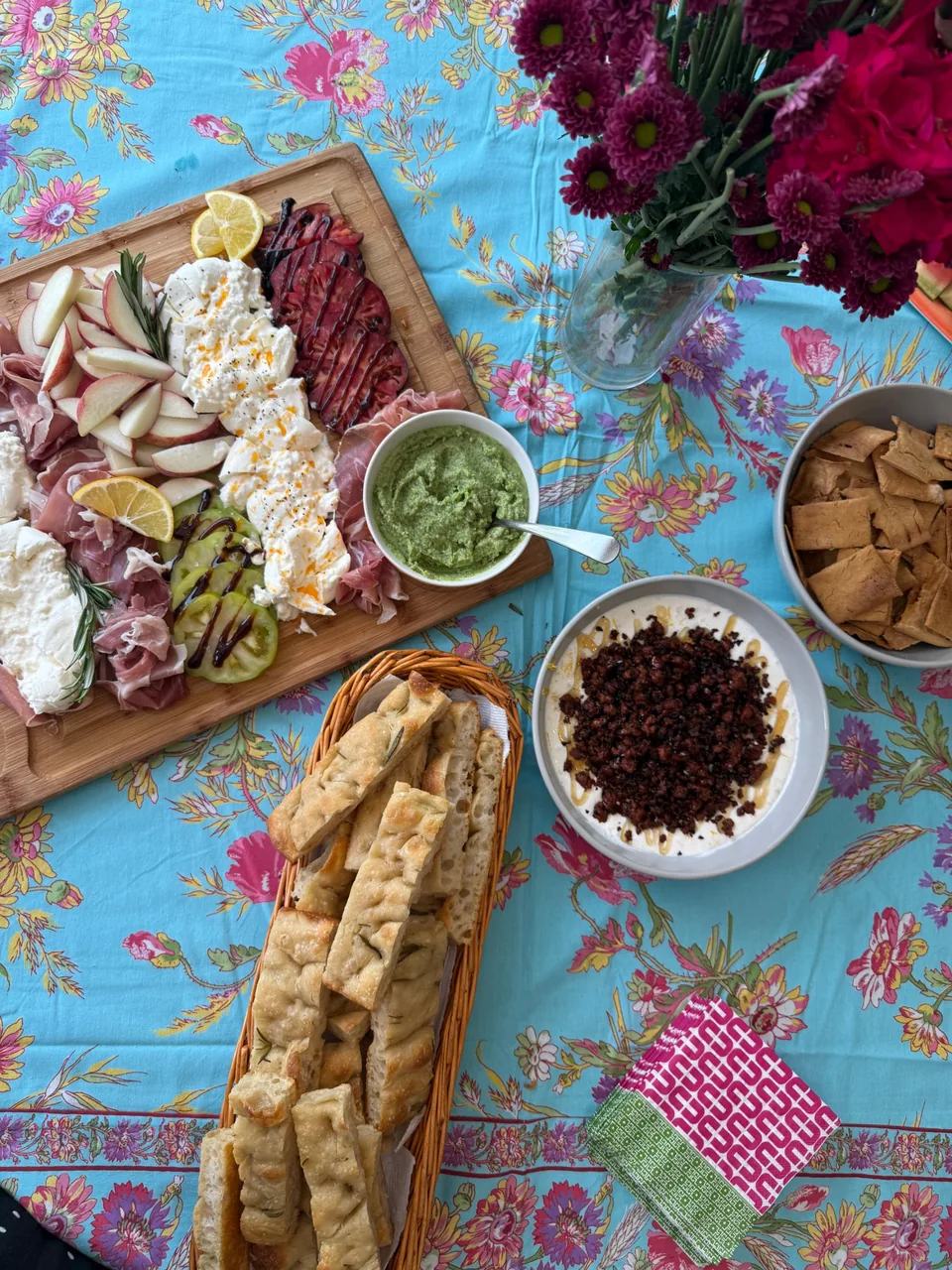 Table spread with a burrata board, pesto, focaccia, crackers and a whipped dip topped with crispy chorizo