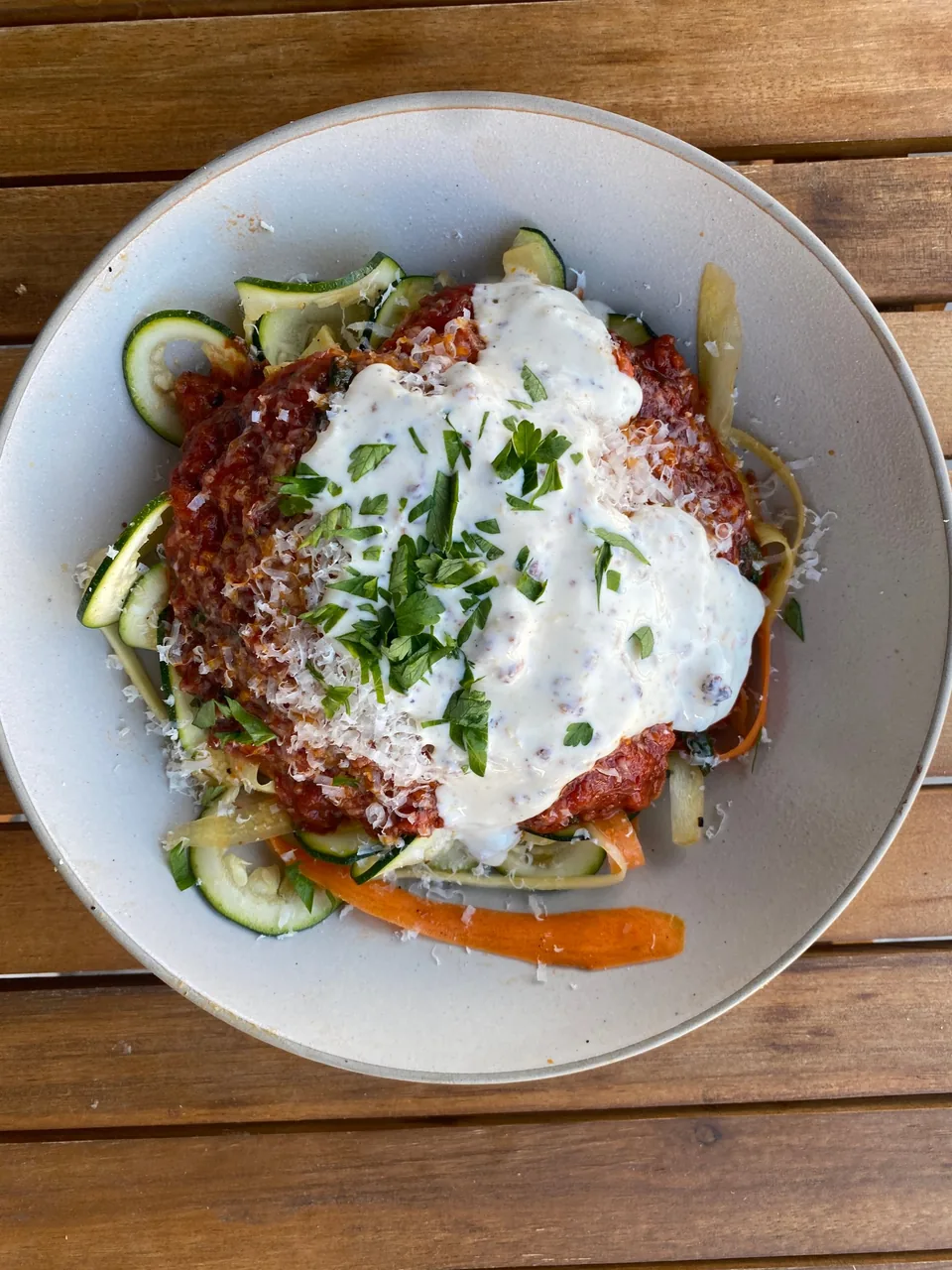 Zucchini and carrot ribbons topped with meat sauce, a creamy white sauce, parmesan and parsley